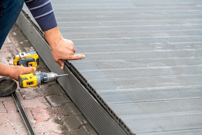 Man assembling composite deck using cordless screwdriver.