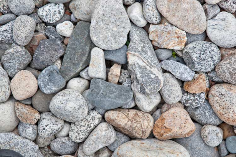 River rocks create a natural transition that softens deck lines and adds texture to your yard