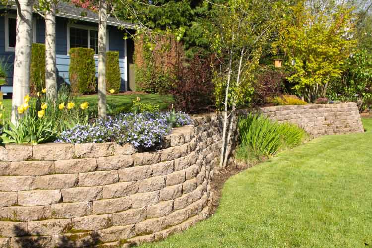 A low retaining wall manages water flow to hold soil and direct runoff away from your yard